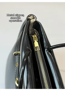 Close-up of smooth gold hardware zipper and inner lining detail on black tote bag