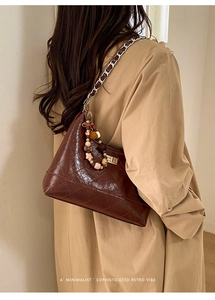 Close-up of brown quilted leather bag with silver chain and cute cartoon charms
