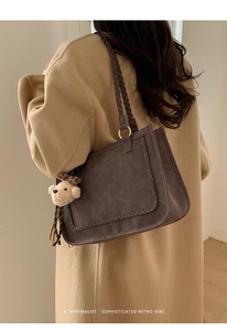 Detail of dark brown tote bag with woven strap accents and a cute plush bear charm