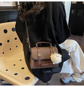 Detail of vintage brown textured crossbody bag with metal rivets and plush sheep charm