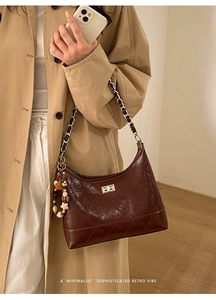 Detail of dark brown quilted shoulder bag featuring gold twist lock and retro beaded charm