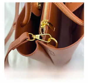 Nahaufnahme der Premium-Lederstruktur mit goldenen Metallteilen an der braunen Handtasche