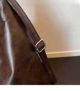 Close-up of adjustable silver metal buckle and premium dark brown leather texture