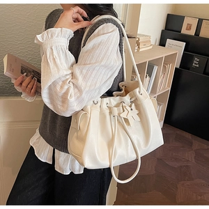 Detail of cream drawstring tote bag with star charm and side pocket on wooden background