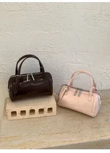 Close-up of vintage oil-waxed leather Boston bags in brown and pink with top handles