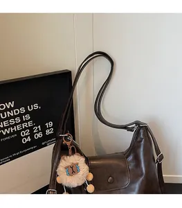 Close-up of brown faux leather hobo bag featuring slim shoulder strap and plush charm