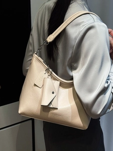 Sac fourre-tout beige minimaliste avec petite pochette porté par un mannequin