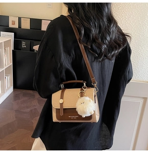 Detailed view of canvas and leather crossbody bag with fluffy charm on a model