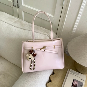 Pink minimalist tote bag with plush bear charm displayed in a cozy interior setting
