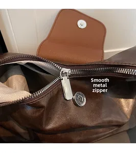 Detail of hardware zipper pull and textured brown leather on a large tote bag