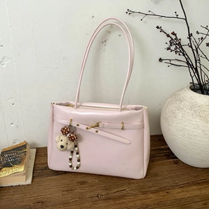 Detailed view of pink tote bag with metal hook, plush charm, and bead accessories