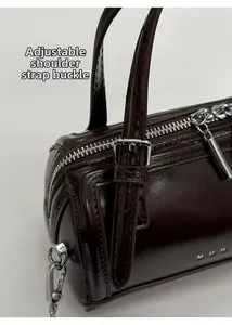 Detail of adjustable silver buckle and glossy dark brown leather on the cylindrical bag