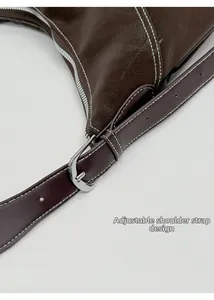 Détail de la bandoulière réglable en cuir marron foncé avec boucle argentée et surpiqûres