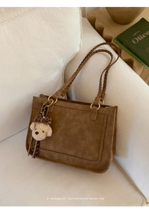 Close-up of brown suede tote bag with woven handles and leopard bow bear pendant