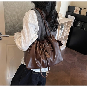 Detail of a dark brown pleated bucket bag with star pendant and large capacity