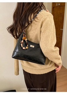 Close-up of black quilted hobo bag with silver turn-lock and cute bear charm detail