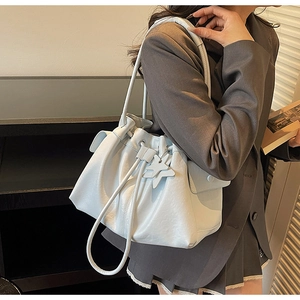 Detailed shot of a white pleated bucket bag with star pendant on a professional model
