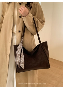 Detail of dark brown suede tote bag with decorative silk scarf on shoulder