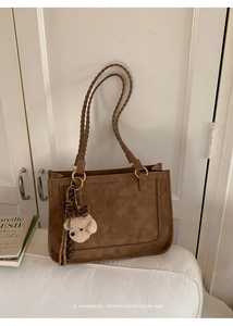 Detail of vintage brown tote bag featuring woven edges and a cute puppy plush charm