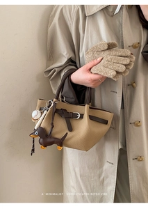 Detail der khakifarbenen Beuteltasche mit Dackel-Anhänger und Baseball-Accessoire