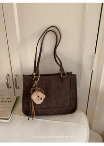 Detailed close-up of dark brown suede tote bag with woven edges and plush bear charm
