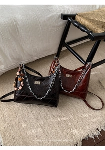 Close-up of quilted hobo bags in black and burgundy with metallic chain straps and textures