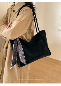 Close-up of black tote bag with printed silk scarf handle detail and matte finish texture