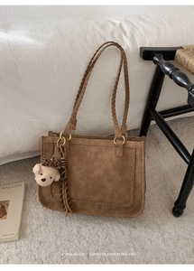 Detail of retro brown suede tote bag with woven straps and cute plush bear charm decoration