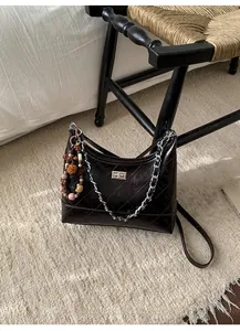 Detail of dark brown quilted leather bag with silver chain and cute plush keychain