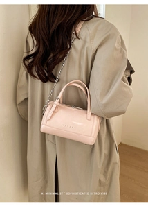 Detail of light pink Boston bag with embossed logo and elegant silver chain strap