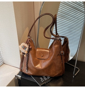 Detailed shot of brown matte leather tote with magnetic flap and lion plush charm decoration