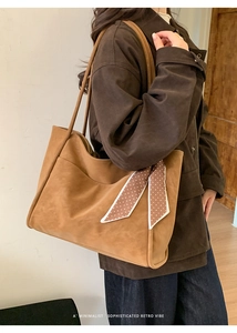 Detail of vintage brown tote bag with matte texture and decorative polka dot silk scarf