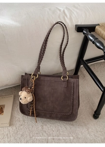 Close-up of deep brown suede tote bag with woven edges and cute bear charm accessory