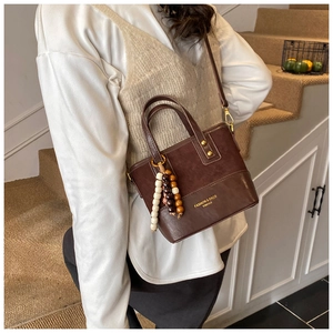 Détail du sac seau marron café avec rivets dorés et pompon en perles colorées