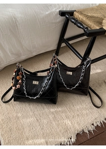 Close-up of quilted black shoulder bags with silver chain straps and turn-lock closure