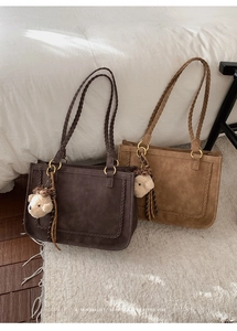 Detail of retro suede tote bags with woven handles and plush bear charms on a bed