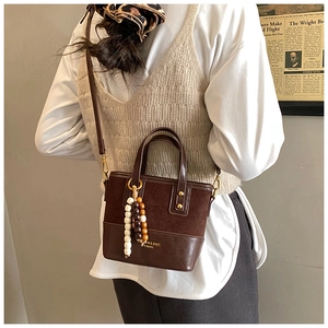 Close-up of brown suede patchwork bucket bag with beads and Fashion text detail