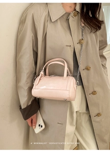 Sac Boston chic en cuir ciré rose clair porté en bandoulière avec une touche vintage