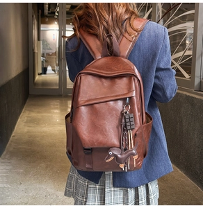 Brown leather backpack detail with lychee texture and cute dog charms on zipper