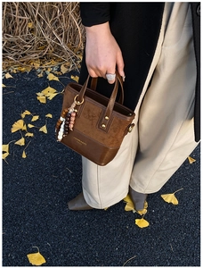 Détail d'un sac seau vintage marron avec empiècements en daim et perles boho