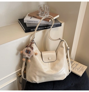 Close-up of hobo bag with flip buckle and cute plush charm on textured seat