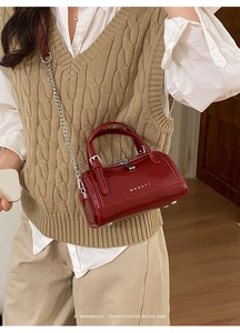 Détail du sac Boston en cuir ciré rouge avec bandoulière chaîne et fermeture éclair
