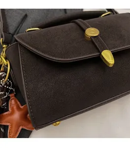 Detalle de bolso de hombro en ante marrón con hebilla dorada y colgante de estrella