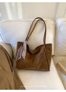 Detailed close-up of dark brown suede tote bag featuring a floral silk scarf on a sofa