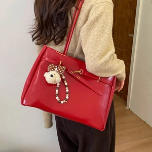 Detail view of red glossy tote bag with cute plush puppy charm and decorative buckle