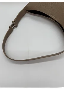 Detalle de la textura de cuero granulado y hebilla ajustable en un bolso de hombro