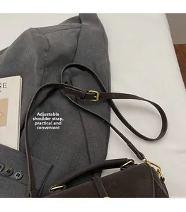 Detalle de la correa ajustable con hebilla dorada en un bolso de ante marrón