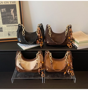 Four vintage hobo bags in black, brown, and cream with gold chains and ethnic tassel charms