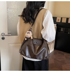 Detail of dark brown vintage leather shoulder bag with cute plush sheep pendant charm
