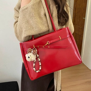Detail of red oversized tote bag with plush bear charm and metallic buckle closure